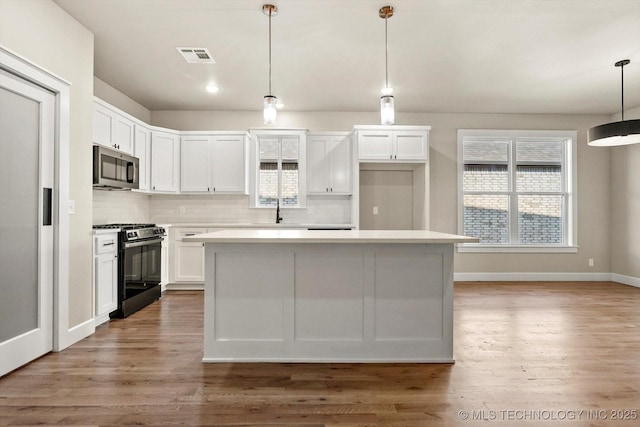 4231 W 4th St, Skiatook, OK 74070 - kitchen with gas range oven, stainless steel microwave, white cabinets, backsplash, and recessed lighting
