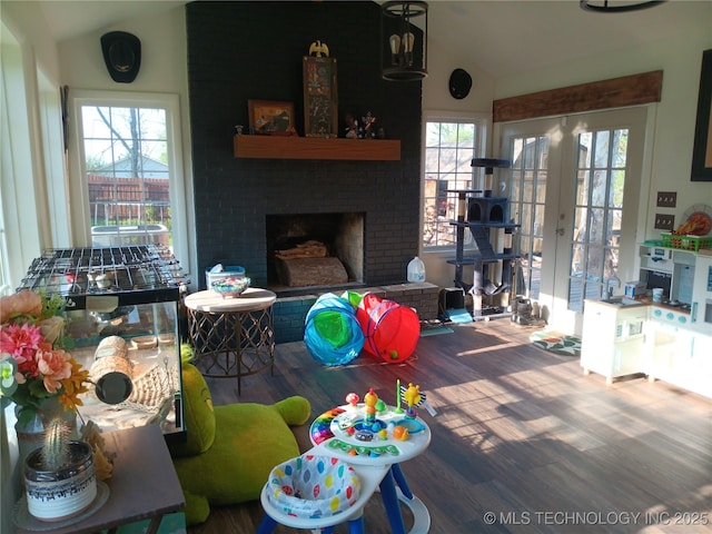 living area with lofted ceiling, french doors, wood finished floors, and a brick fireplace