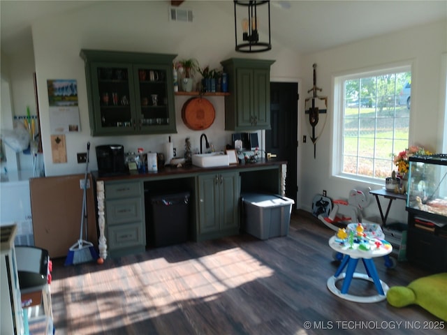 kitchen with dark wood-style floors, a sink, glass insert cabinets, lofted ceiling, and dark countertops
