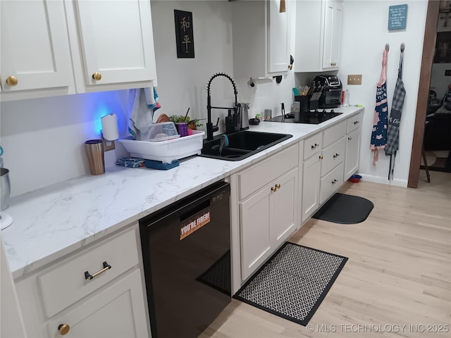kitchen featuring black appliances, a sink, light wood-style floors, white cabinetry, and light stone countertops