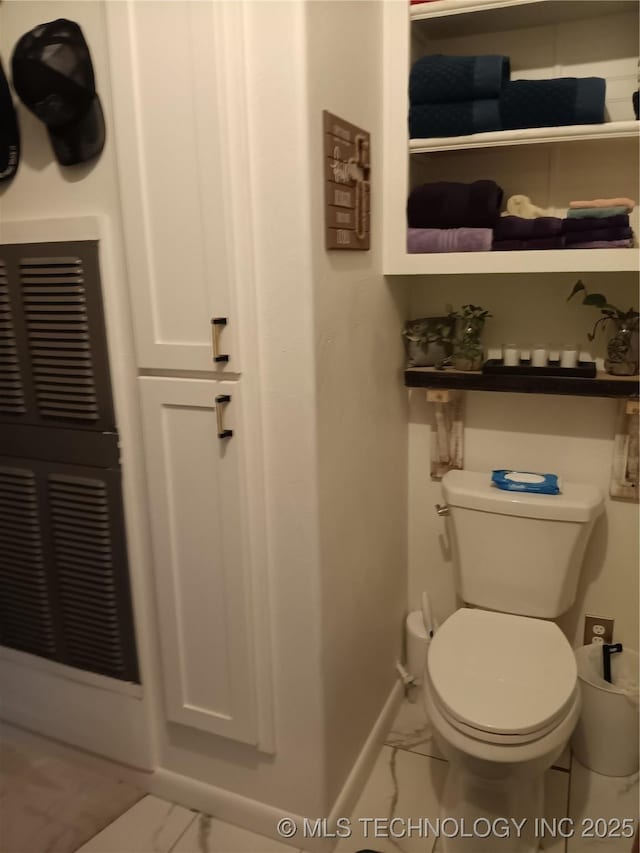 bathroom featuring marble look tile flooring, toilet, and baseboards