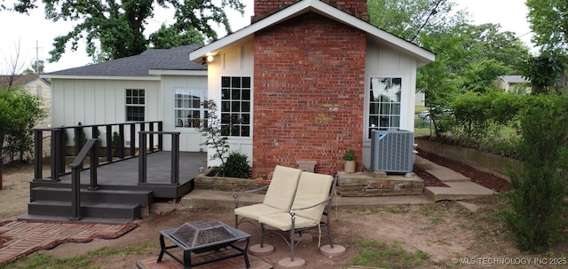 rear view of property with a chimney, central air condition unit, an outdoor fire pit, roof with shingles, and a patio
