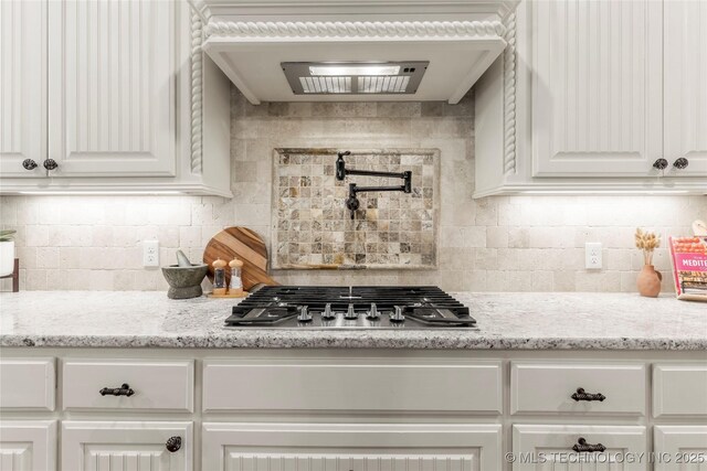 kitchen with stainless steel gas stovetop, backsplash, and white cabinetry