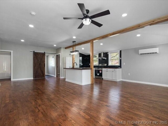 322 W Seneca St, Nowata, OK 74048 - unfurnished living room with a barn door, ceiling fan, a wall unit AC, dark wood-style floors, and recessed lighting