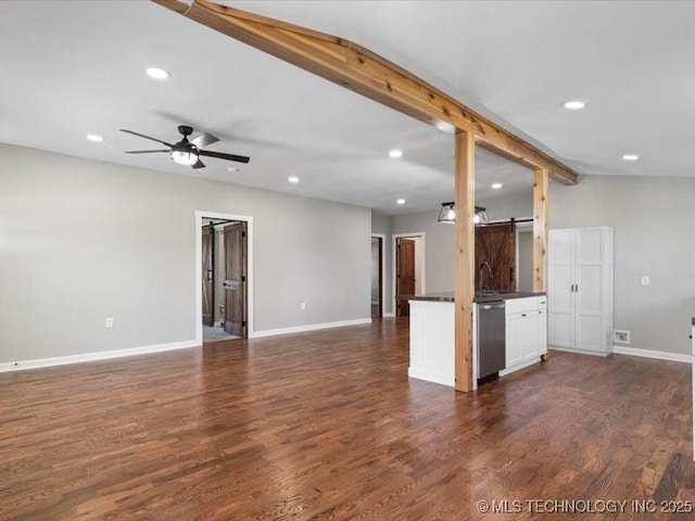 322 W Seneca St, Nowata, OK 74048 - unfurnished living room featuring dark wood-style flooring, baseboards, recessed lighting, and a barn door