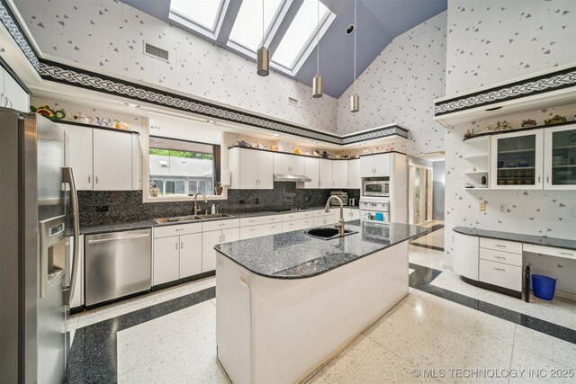 kitchen featuring high vaulted ceiling, a skylight, appliances with stainless steel finishes, and a sink
