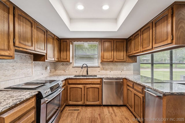 501 E Yuma Dr, Broken Arrow, OK 74011 - kitchen with appliances with stainless steel finishes, light wood-style floors, a raised ceiling, a peninsula, and light stone countertops