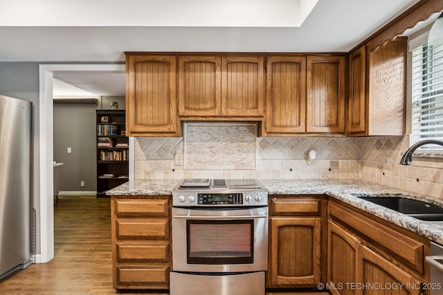 501 E Yuma Dr, Broken Arrow, OK 74011 - kitchen with stainless steel appliances, wood finished floors, decorative backsplash, light stone countertops, and brown cabinetry