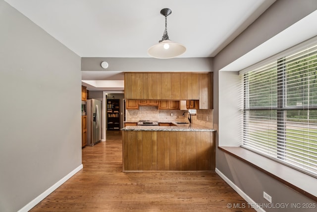 501 E Yuma Dr, Broken Arrow, OK 74011 - kitchen featuring brown cabinets, stainless steel fridge, a peninsula, backsplash, and light wood-style floors
