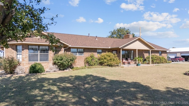 back of property with a lawn, a chimney, brick siding, and roof with shingles