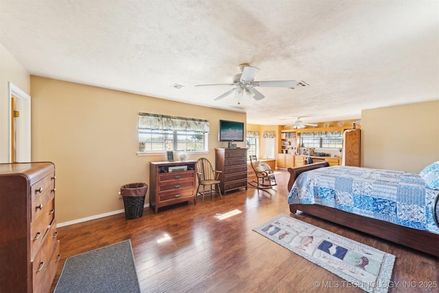 bedroom with visible vents, baseboards, wood finished floors, and multiple windows