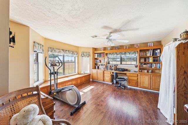 home office with a ceiling fan, a wealth of natural light, a textured ceiling, and dark wood-style flooring