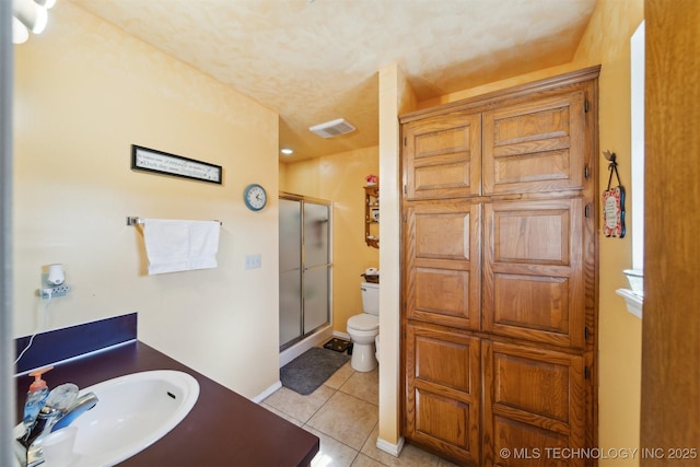 bathroom featuring a sink, a stall shower, toilet, tile patterned flooring, and visible vents