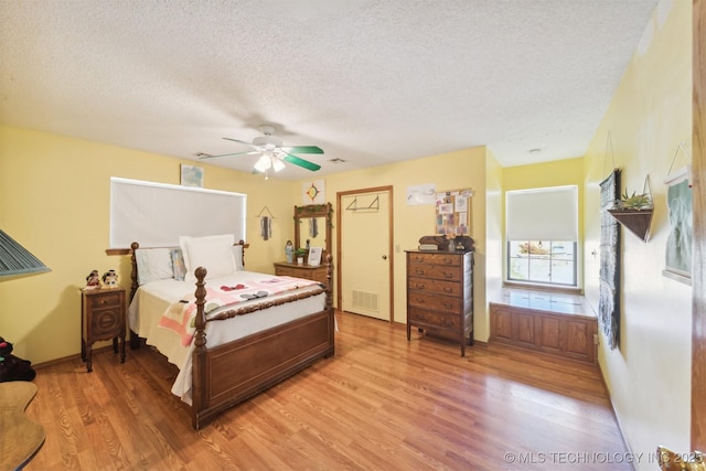 bedroom with light wood finished floors, visible vents, a textured ceiling, and multiple windows