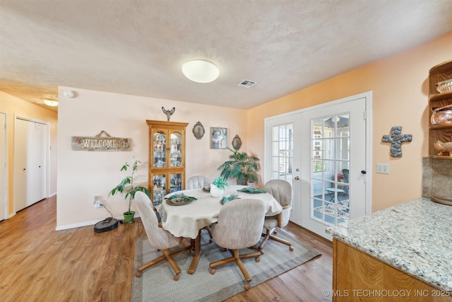 dining room featuring light wood-style floors, visible vents, baseboards, and french doors