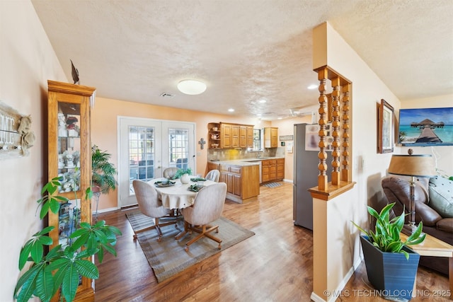 dining space featuring recessed lighting, light wood-type flooring, a textured ceiling, and baseboards