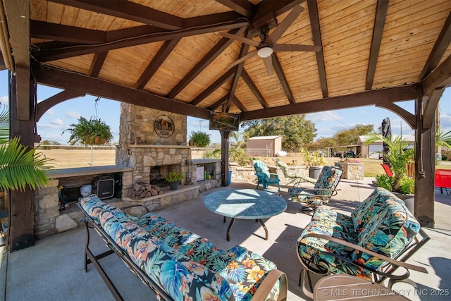 view of patio / terrace with a gazebo, an outdoor living space with a fireplace, ceiling fan, and fence