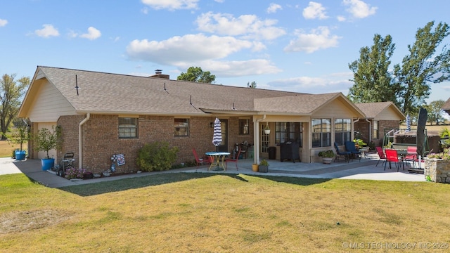 back of property with brick siding, a lawn, and a patio