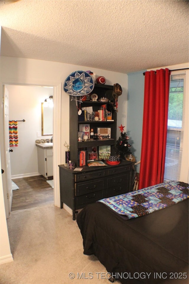 9996 N Millennium, Sulphur, OK 73086 - bedroom with connected bathroom, carpet floors, a sink, baseboards, and a textured ceiling