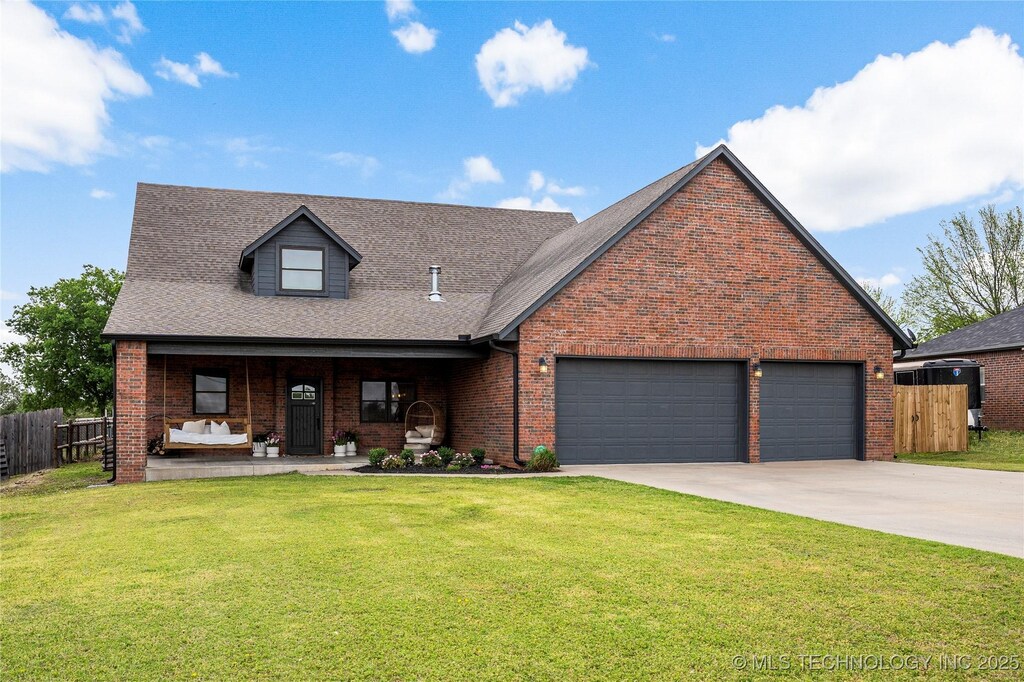 2191 S Osage St, Skiatook, OK 74070 - view of front of home featuring a porch, concrete driveway, fence, an attached garage, and a front yard