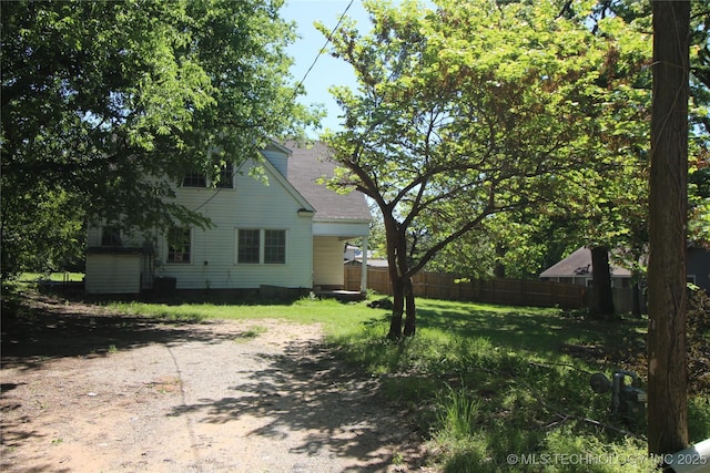 view of yard with dirt driveway and fence