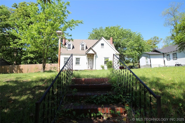 view of front of house featuring a front yard, a chimney, and fence
