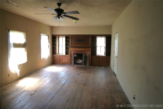 unfurnished living room featuring ceiling fan, a brick fireplace, and hardwood / wood-style floors