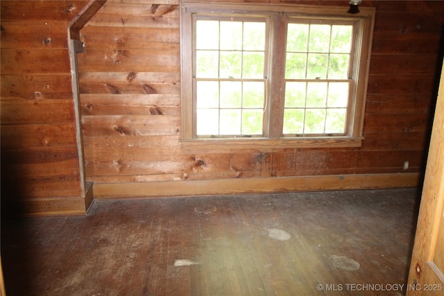 unfurnished room with hardwood / wood-style flooring and wood walls
