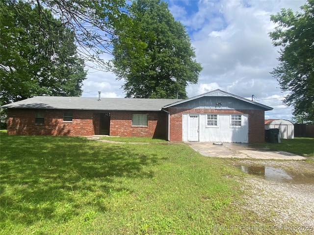 1320 Jennings St, Muskogee, OK 74403 - back of house featuring brick siding, a yard, a patio, a storage shed, and an outbuilding