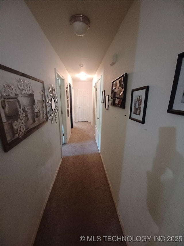 hall with baseboards and light colored carpet