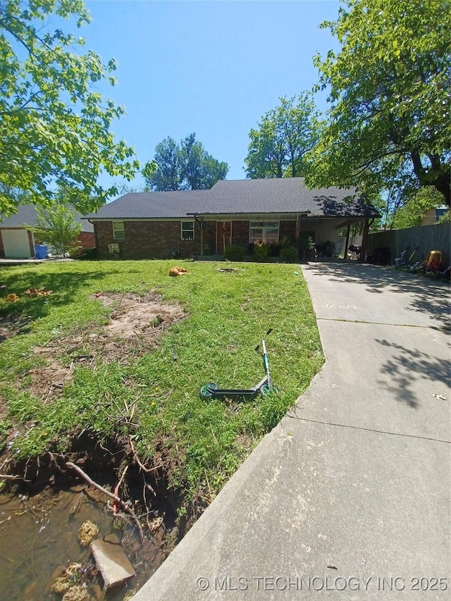 ranch-style home with driveway, an attached carport, and a front yard