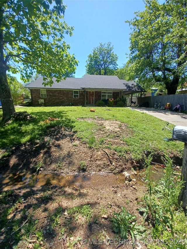 view of front of house featuring a front lawn, fence, and a carport