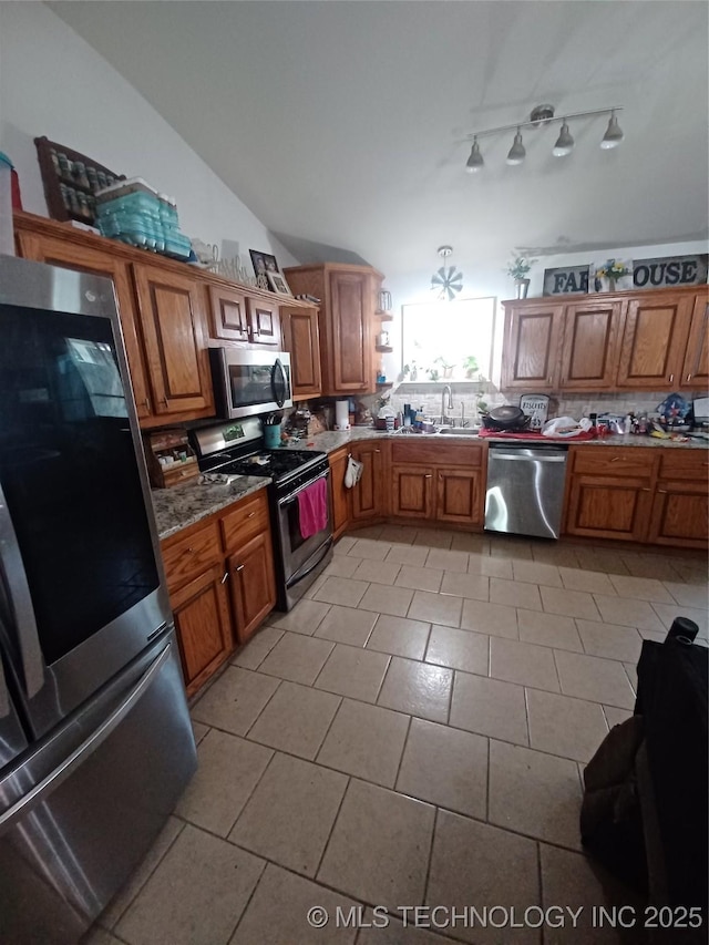 kitchen featuring tasteful backsplash, a sink, brown cabinets, light tile patterned floors, and stainless steel appliances