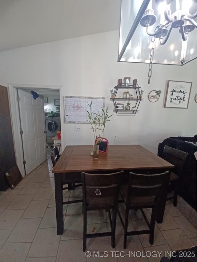 dining space featuring an inviting chandelier, light tile patterned floors, and washer / dryer