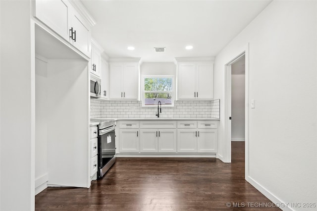 kitchen with light countertops, decorative backsplash, white cabinetry, and stainless steel appliances