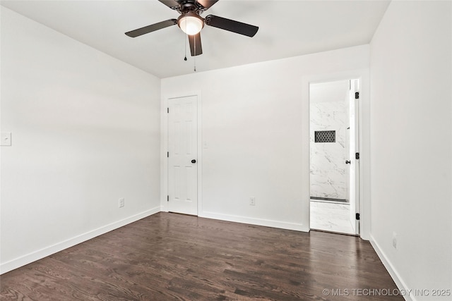 empty room featuring dark wood finished floors, a ceiling fan, and baseboards
