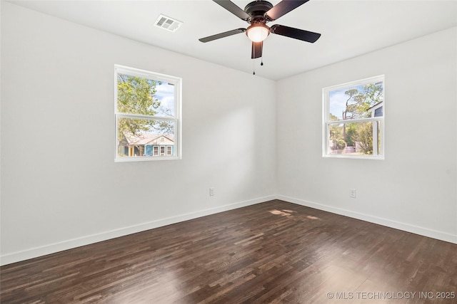 empty room featuring dark wood-type flooring, a healthy amount of sunlight, and baseboards