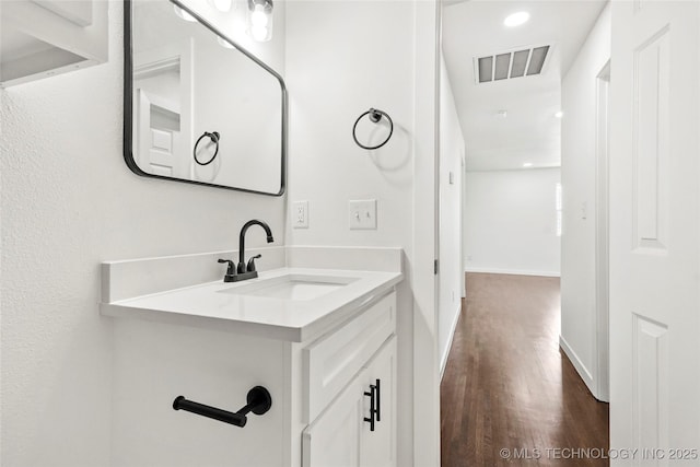 bathroom with wood finished floors, vanity, baseboards, visible vents, and recessed lighting