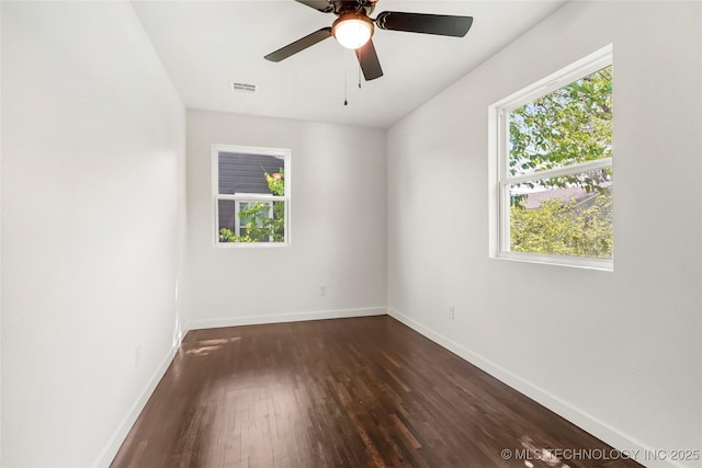 spare room with baseboards, dark wood-style floors, and a wealth of natural light