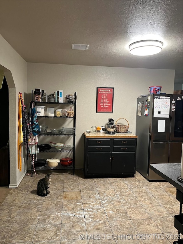 27121 E 161st St S, Coweta, OK 74429 - kitchen with freestanding refrigerator, dark cabinetry, arched walkways, a textured ceiling, and light countertops