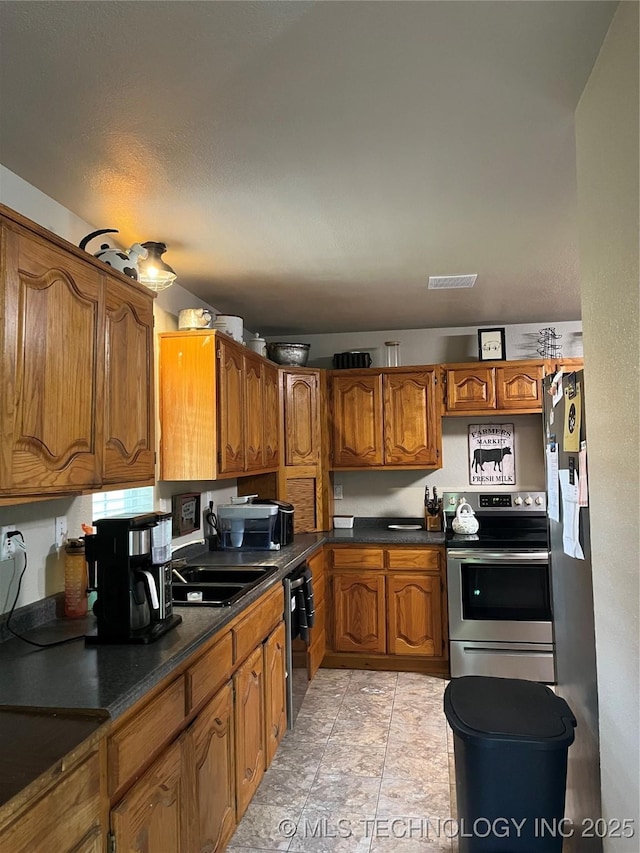 27121 E 161st St S, Coweta, OK 74429 - kitchen with stainless steel appliances, brown cabinetry, a sink, and dark countertops