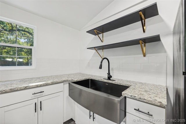 1910 E Marshall Pl, Tulsa, OK 74110 - kitchen with a sink, backsplash, white cabinetry, light stone counters, and vaulted ceiling