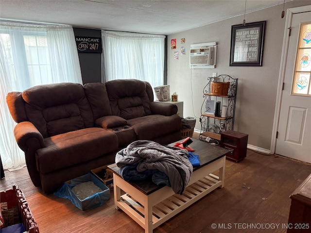 713 6th Ave, Warner, OK 74469 - living area with wood finished floors, a wall mounted AC, and a textured ceiling