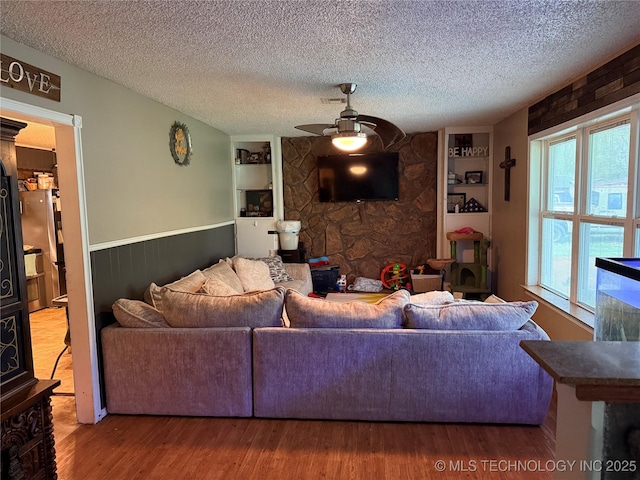 713 6th Ave, Warner, OK 74469 - living room featuring wood finished floors, a textured ceiling, built in shelves, and ceiling fan