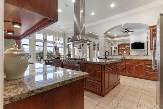 5905 W Charleston St, Broken Arrow, OK 74011 - kitchen featuring island exhaust hood, ceiling fan, arched walkways, a center island with sink, and stove