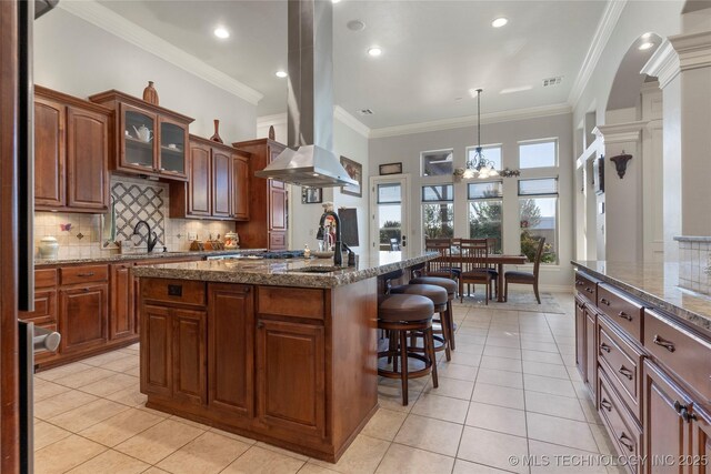 5905 W Charleston St, Broken Arrow, OK 74011 - kitchen featuring island exhaust hood, a kitchen breakfast bar, light tile patterned flooring, tasteful backsplash, and a notable chandelier