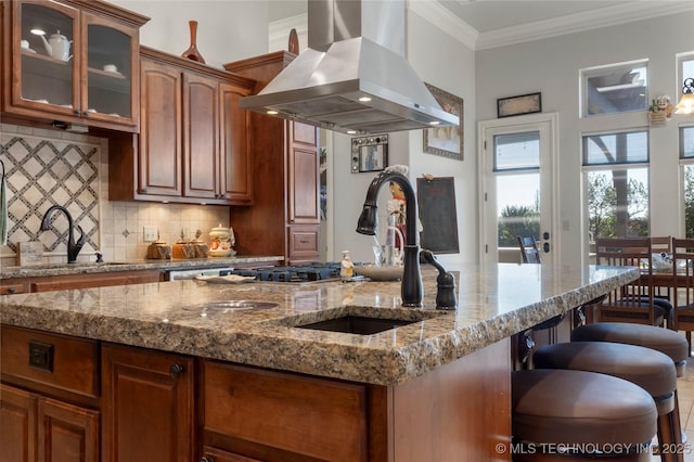 5905 W Charleston St, Broken Arrow, OK 74011 - kitchen featuring island exhaust hood, a sink, decorative backsplash, glass insert cabinets, and an island with sink