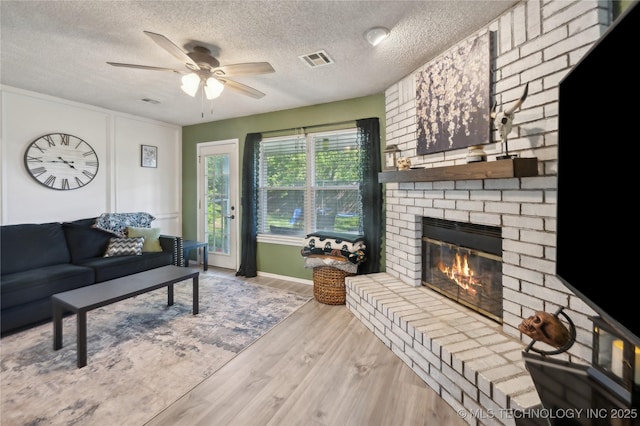 115 Aspen Dr, Mannford, OK 74044 - living area featuring a ceiling fan, a brick fireplace, a textured ceiling, and visible vents