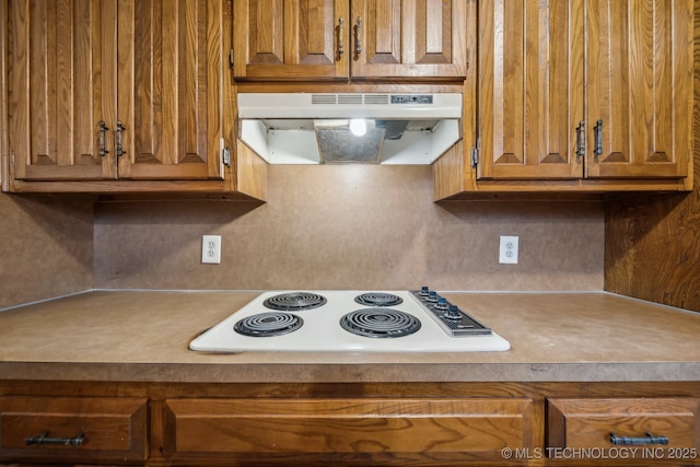 3316 S Ash Pl, Broken Arrow, OK 74012 - kitchen with under cabinet range hood, brown cabinetry, white electric cooktop, and light countertops