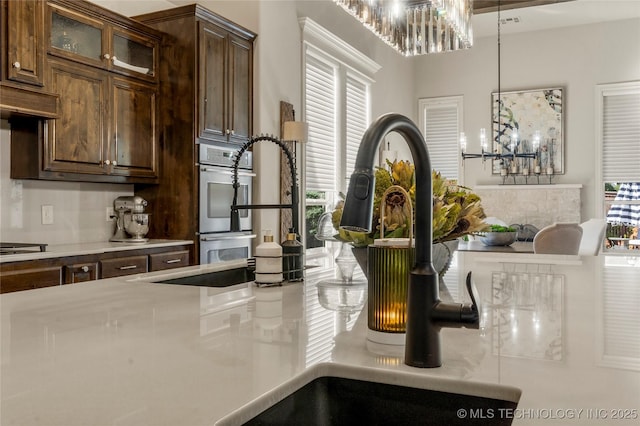 4416 S Orange Ave, Broken Arrow, OK 74011 - interior details with dark brown cabinets, a chandelier, glass insert cabinets, stainless steel double oven, and light countertops
